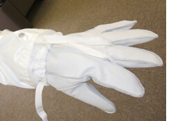 防護服袖部分の紐を手袋の中指に引っ掛けて固定する。